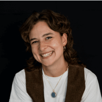 Sophie Sandberg smiling at the camera against a black background.